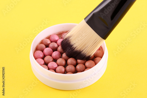 cosmetic brush and rouge on the yellow background