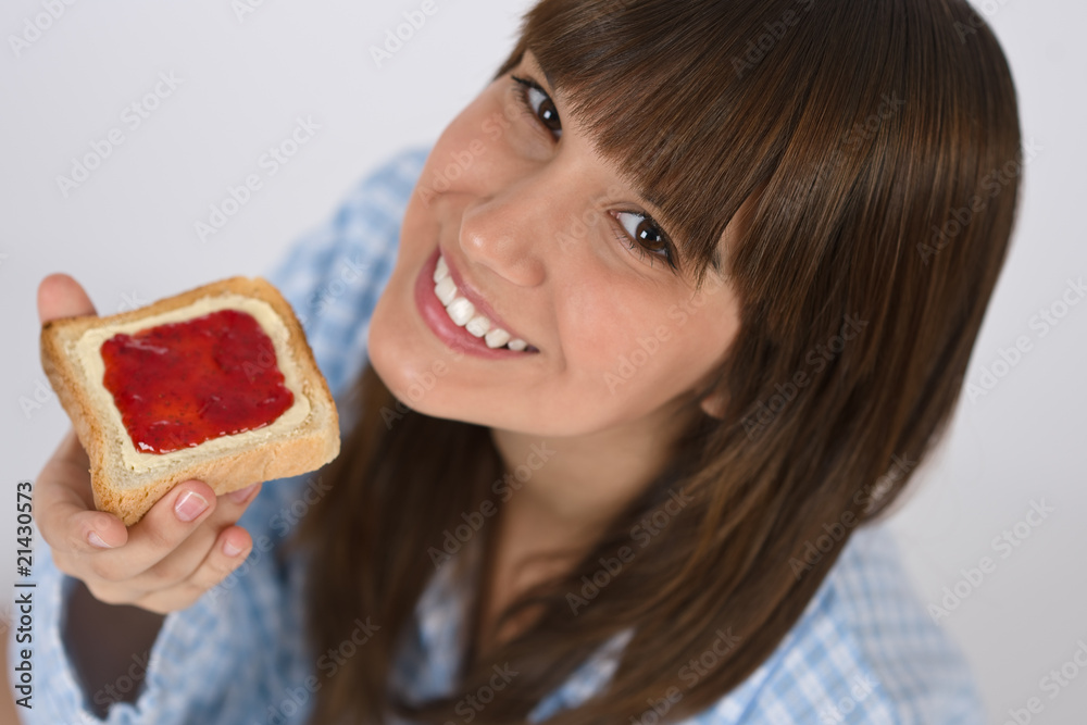 Happy teenager in pajamas eating healthy toast Happy teenager in pajamas eating healthy toast