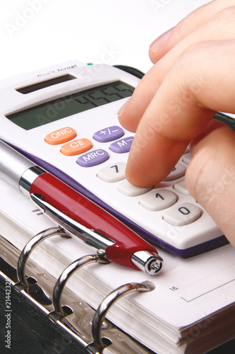 Fingers typing on a calculator with a pen an organiser photo