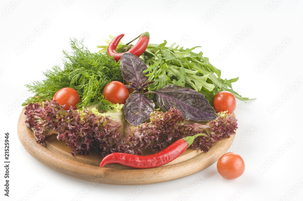 Fresh raw herbs and vegetables on cutting board over white Fresh raw herbs and vegetables on cutting board over white
