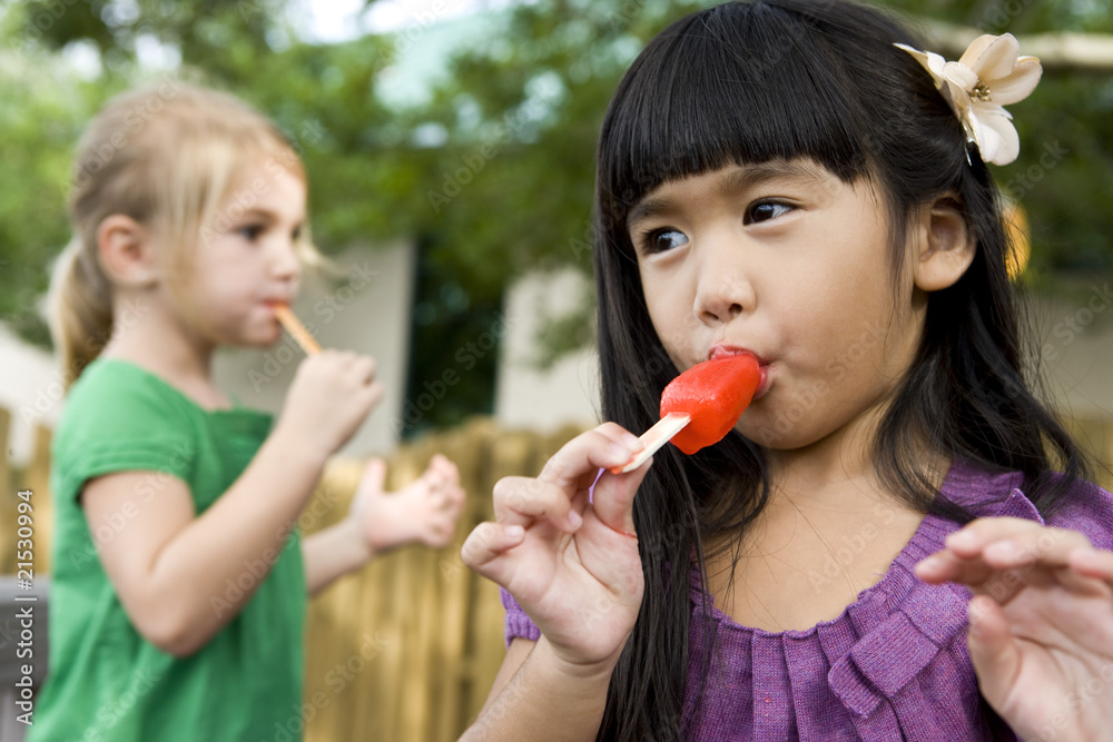 Close-up of two preschool girls eating popsicles Close-up of two preschool girls eating popsicles