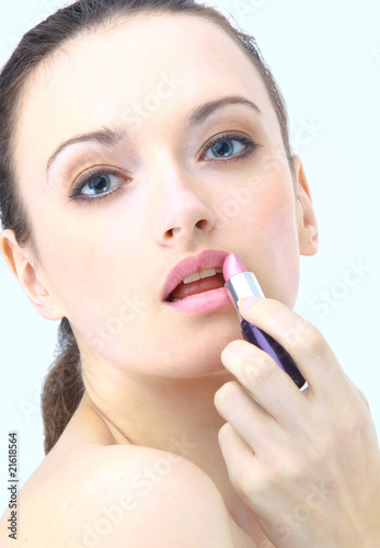 Portrait of beautiful woman applying lipstick using lip brush.