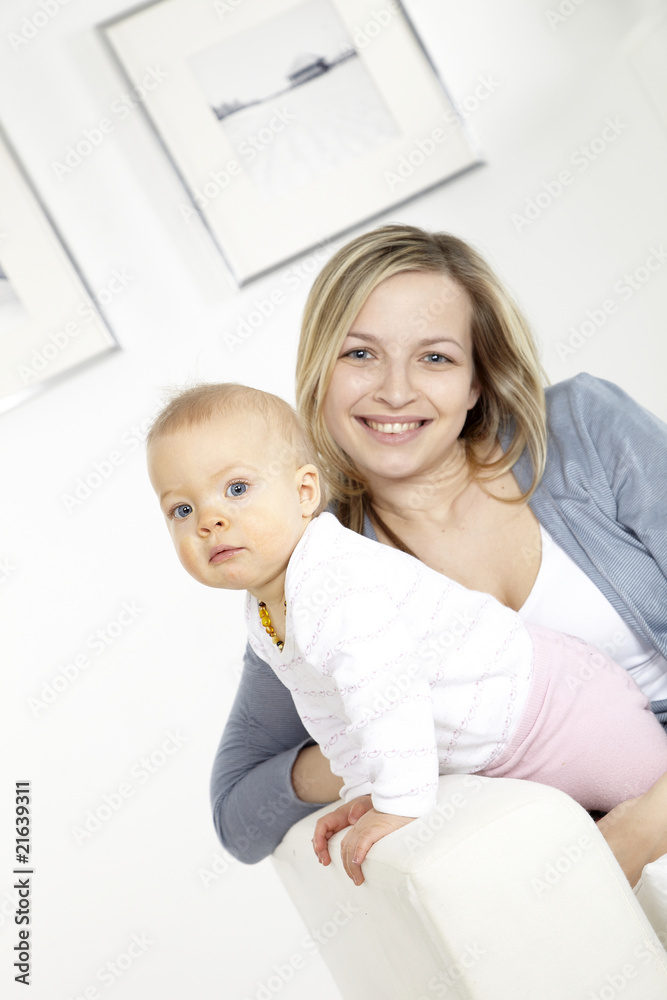 junge mutter mit baby auf weißem sofa junge mutter mit baby auf weißem sofa