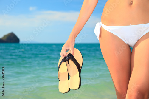 woman holding a pair of flip flops in the water