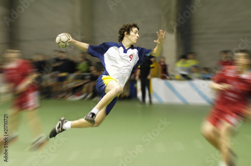 Photographie young handball player on a match jumping to score a goal