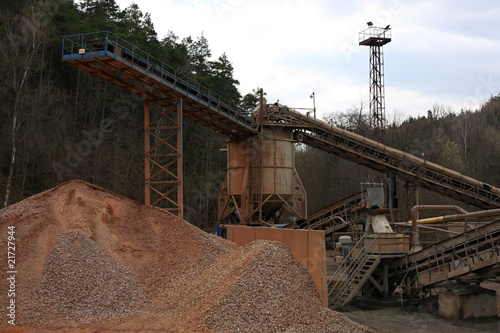 Stone quarry with silos, conveyor belts and piles of stones.