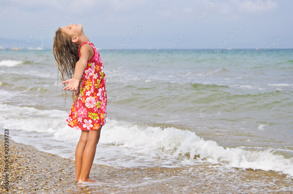 Sweet beautiful girl in a bright dress looks on the sea