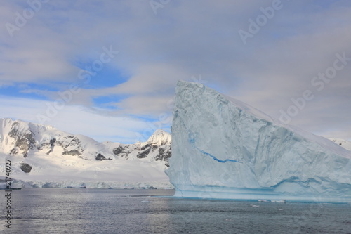 Iceberg and landscape in Antarctica with clouds in background