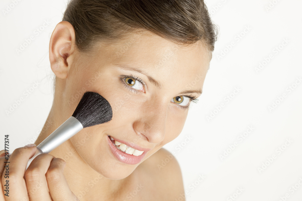 portrait of young woman putting on face powder portrait of young woman putting on face powder
