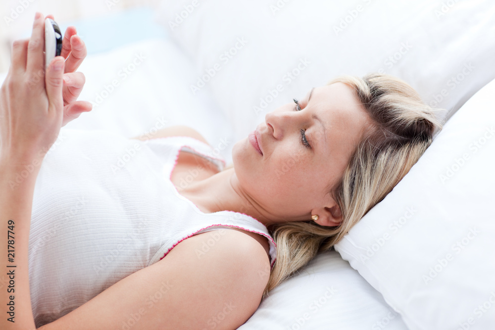 Concentrated woman sending a text lying on a bed Concentrated woman sending a text lying on a bed