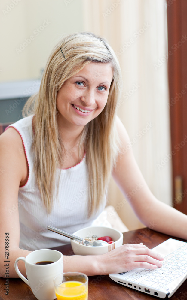 Charming woman using a laptop while having a breakfast Charming woman using a laptop while having a breakfast