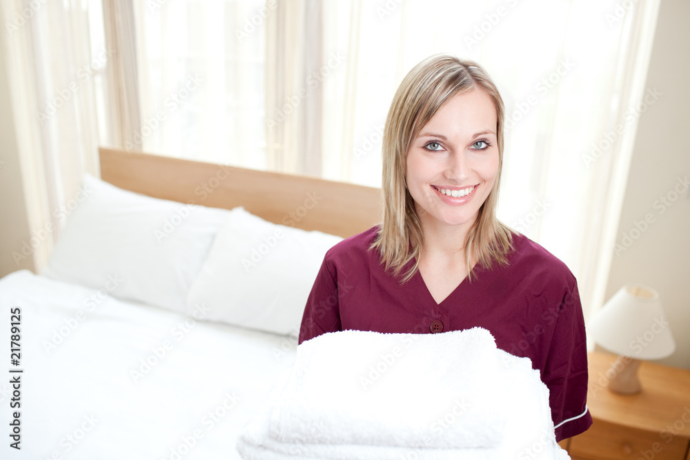 Radiant cleaning lady holding towels in a hotel room Radiant cleaning lady holding towels in a hotel room