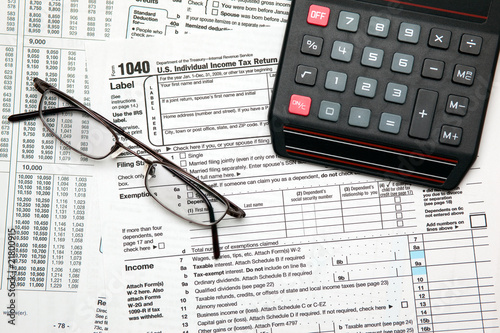 Tax time - Closeup of U.S. 1040 tax return with calculator and g