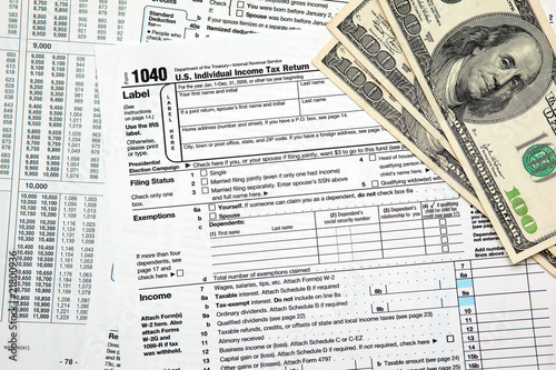 Tax time - Closeup of U.S. 1040 tax return with $100 bills