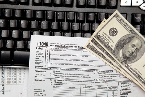 Tax time - Closeup of U.S. 1040 tax return with $100 bills and c
