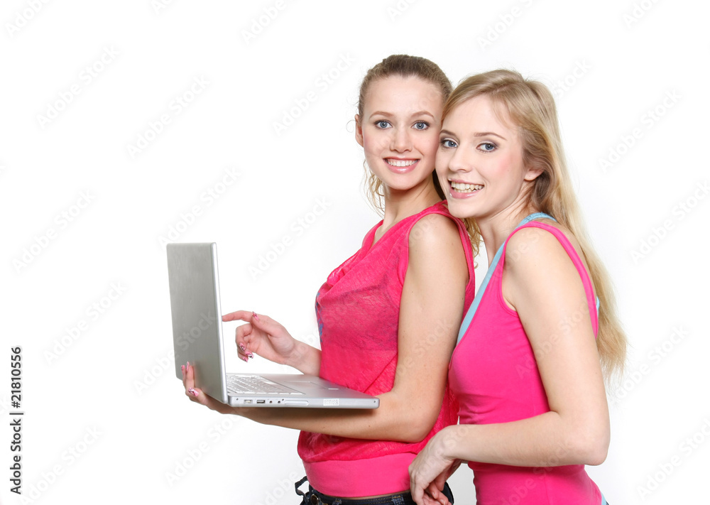 two young smiling girls with laptop over white two young smiling girls with laptop over white