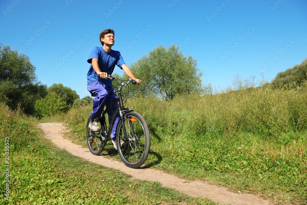 man wearing sporty clothes is riding on bycicle. summer day