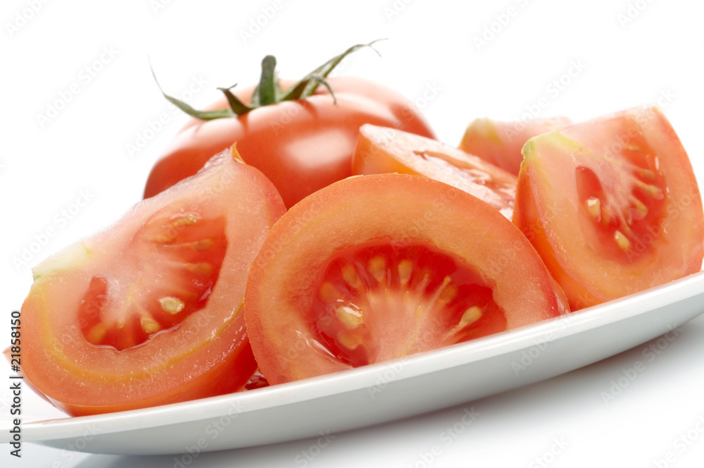 Tomato and tomato slices on white plate Tomato and tomato slices on white plate