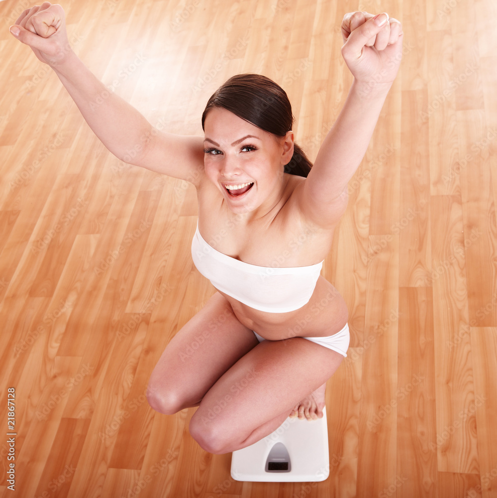 Fototapeta premium Happy girl on scales. Weight-loss.