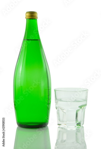 Bottle and glass of mineral water reflected on white background