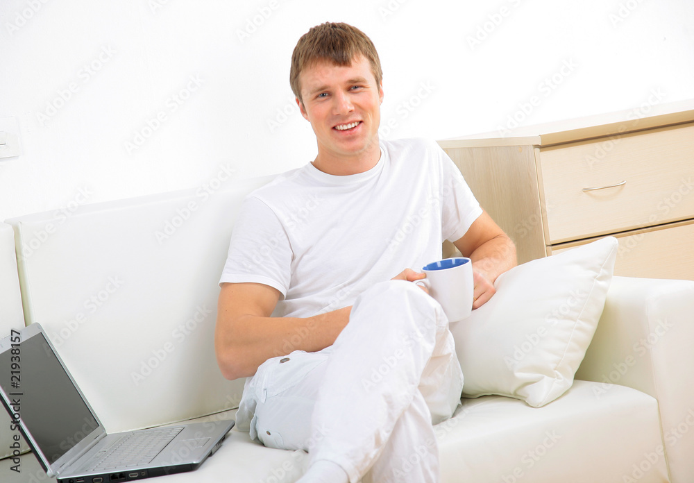 Smiling young man working on laptop computer at home. Smiling young man working on laptop computer at home.
