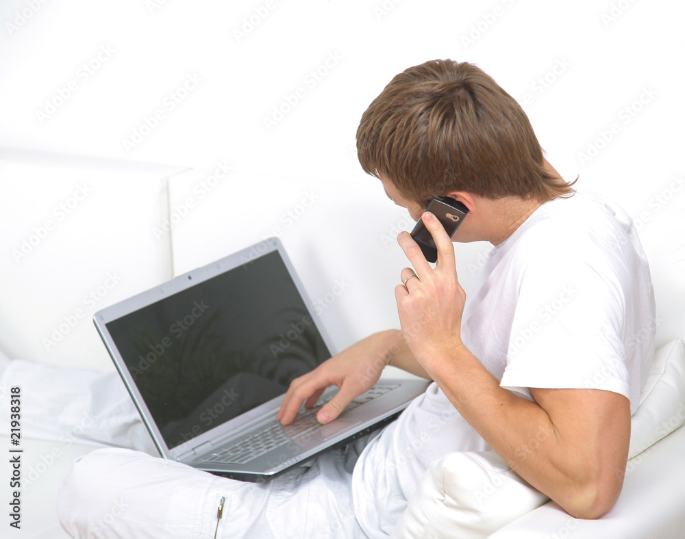 Portrait of a young man speaking on mobile phone with a laptop Portrait of a young man speaking on mobile phone with a laptop