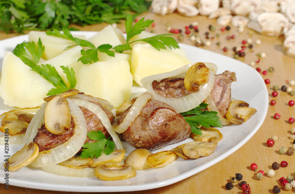 Filet with mushroomgravy, onions and potatoes on wooden plate Filet with mushroomgravy, onions and potatoes on wooden plate