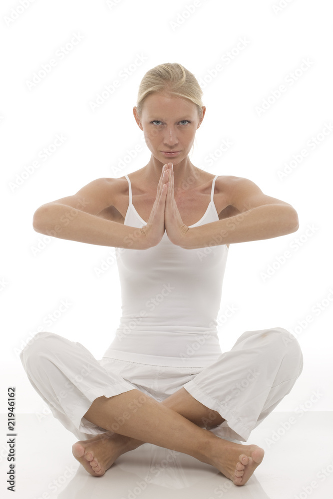young  woman dressed in white sitting cross-legged doing yoga