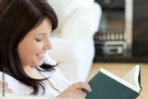 Attractive woman reading a book lying on a sofa