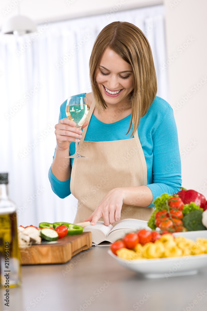 Cooking - Smiling woman reading recipe from cookbook