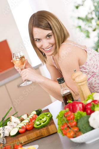 Cooking - smiling woman with glass of white wine and vegetable