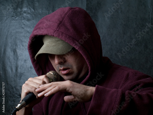 rapper wearing hood and singing to a microphone