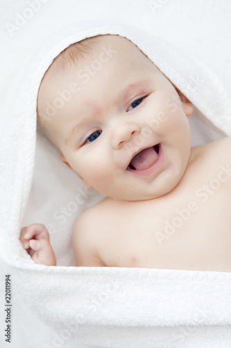 laughing baby after bath, wrapped in white towel