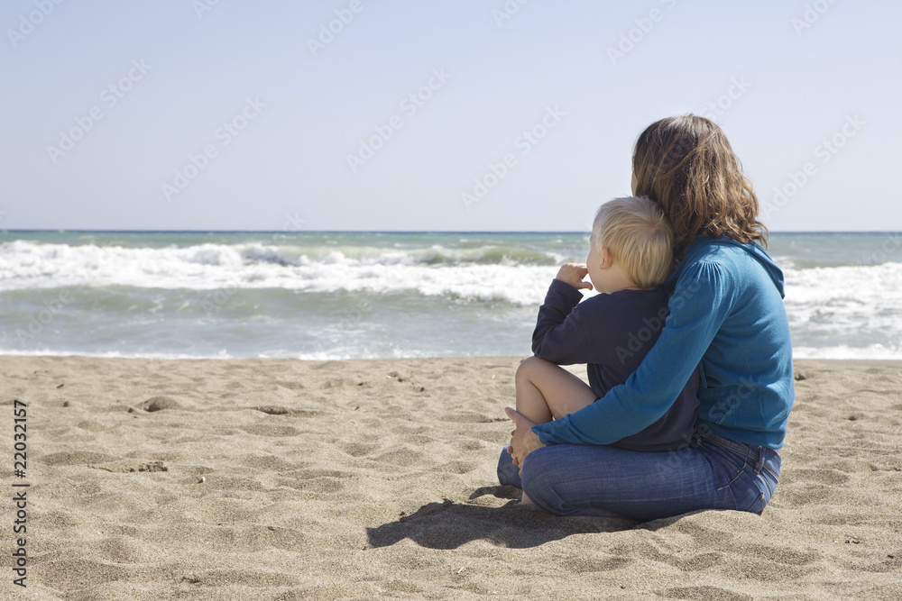 mother sitting with son nearby sea