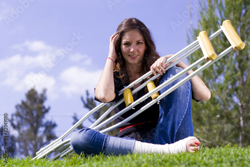Woman seated with crutches outside
