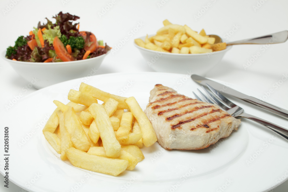 Schweinesteak vom Grill mit Pommes frites und Salat Schweinesteak vom Grill mit Pommes frites und Salat