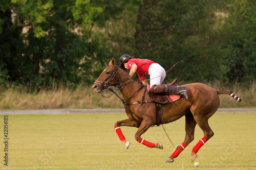 Polo player hitting ball back towards his own goal end