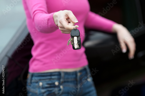 frau mit schlüssel lehnt am auto