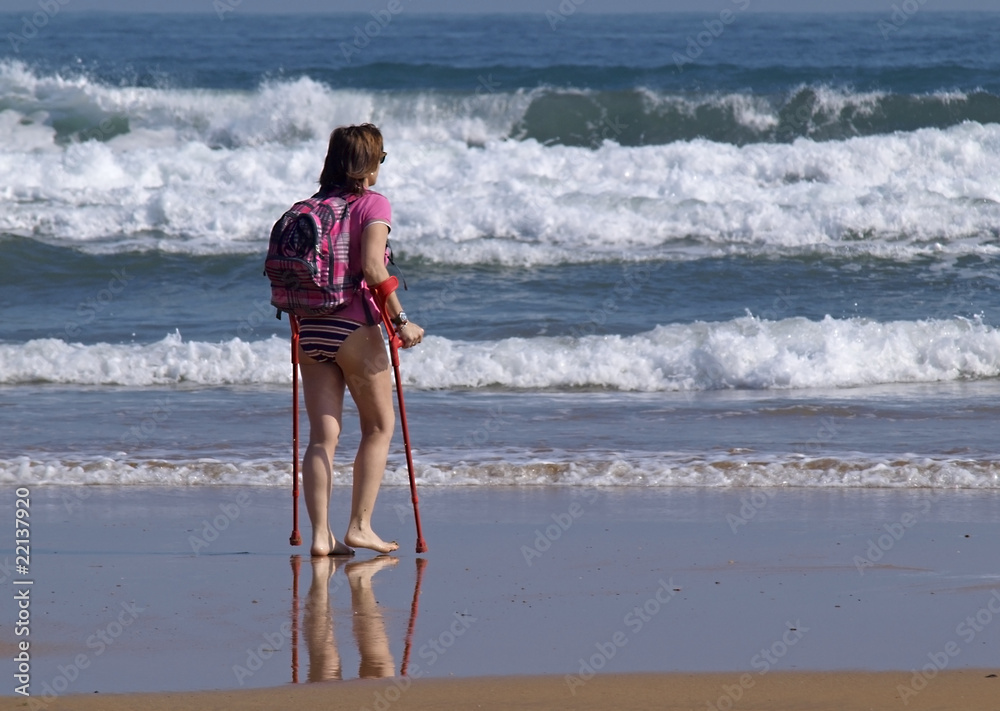 Mujer con muletas en la playa Stock Photo