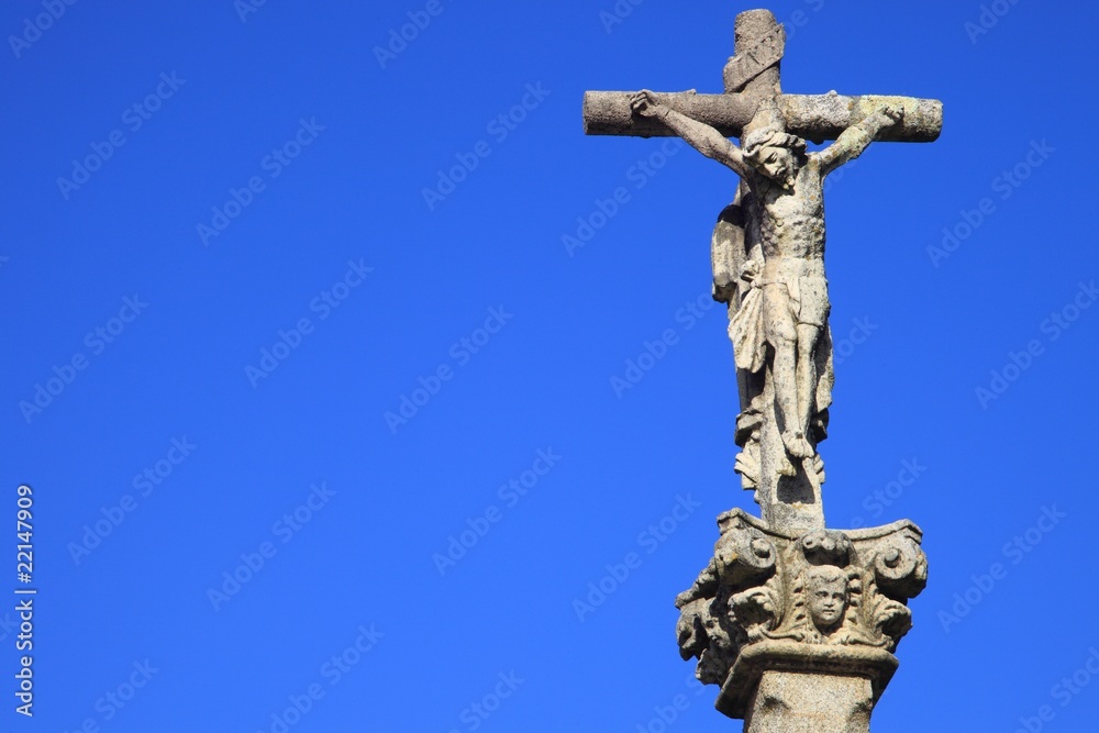 Jesus Christus am Kreuz, Steinfigur vor blauem Himmel