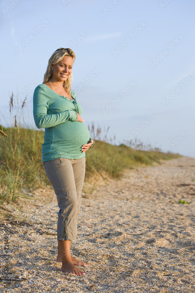 Happy young pregnant woman standing outdoors at beach Happy young pregnant woman standing outdoors at beach
