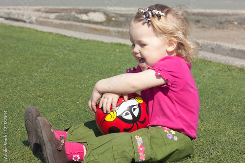 The little girl sitting on the grass.