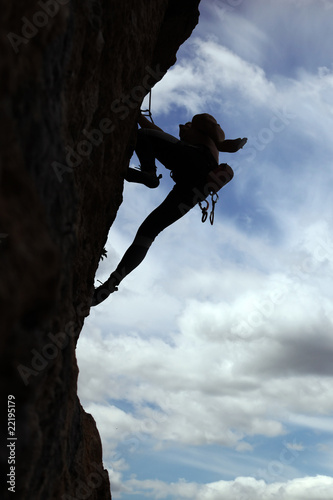 Silhouette of rock climber climbing a cliff