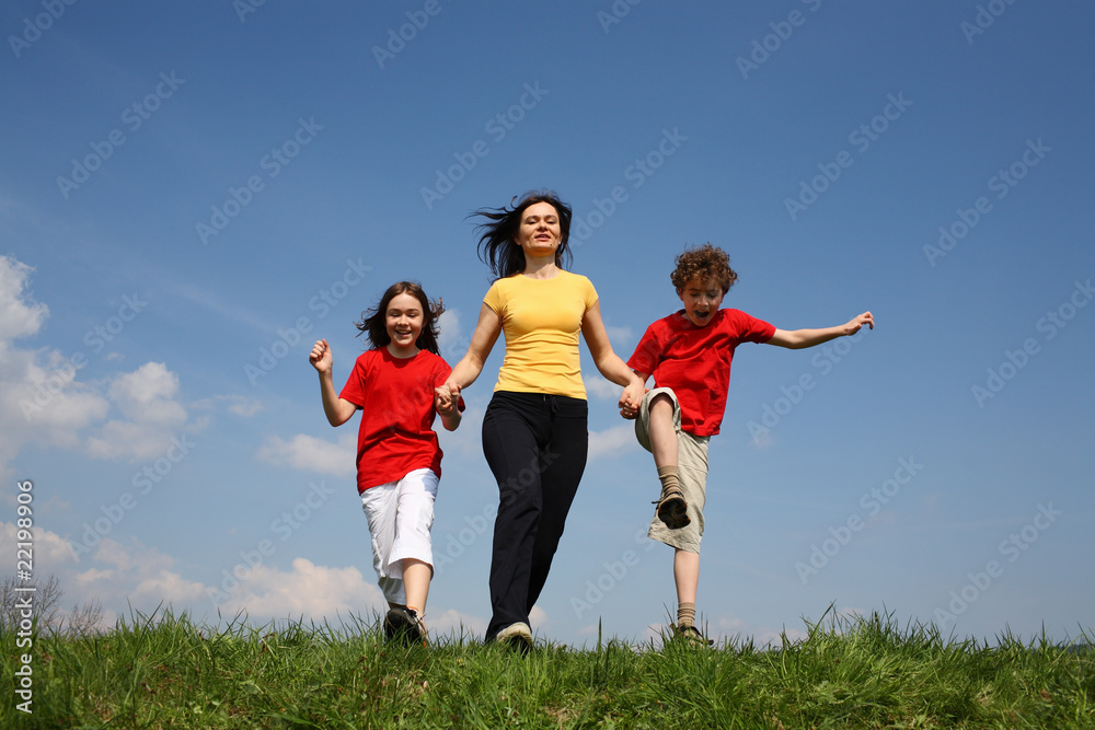 Active family - mother and kids running on green meadow Active family - mother and kids running on green meadow