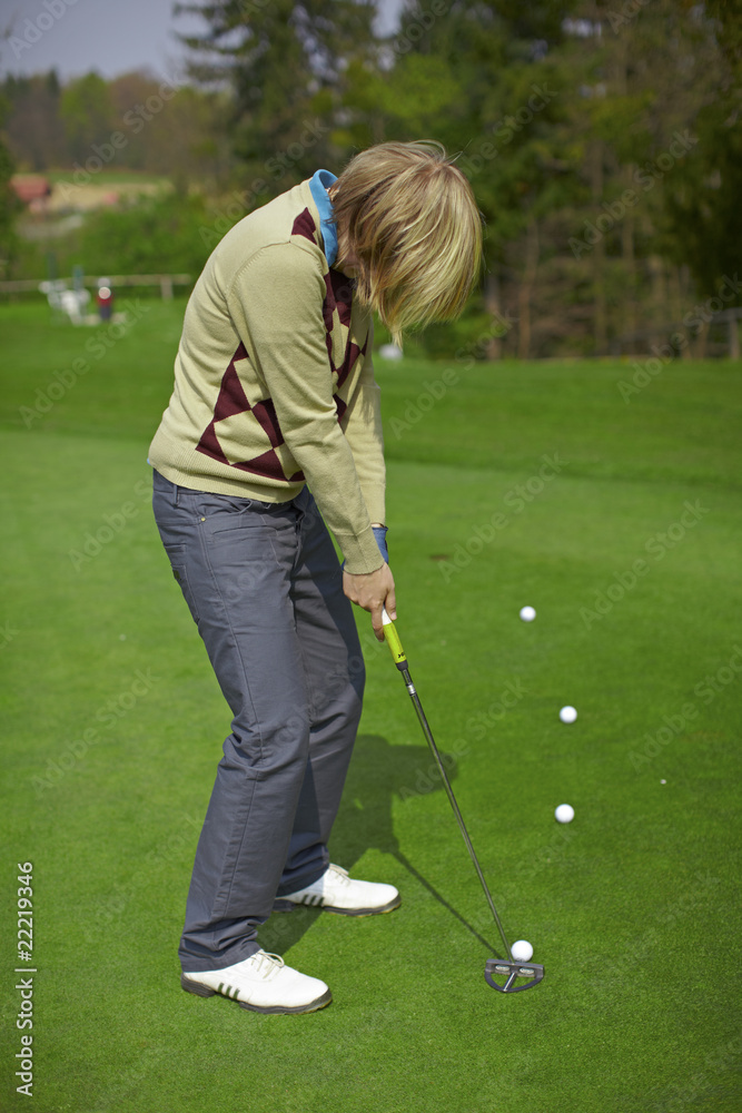 Fototapeta premium Woman golfer practicing putting on a green