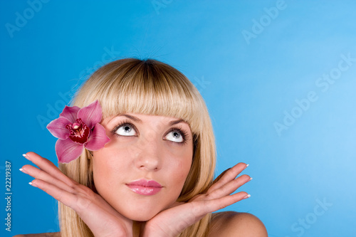 Fresh portrait of a young and beautiful woman with a pink flower