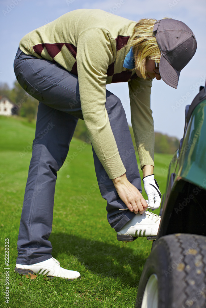 Woman tying shoes at the golf course
