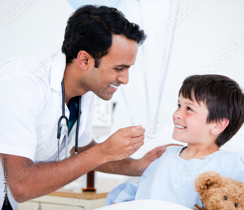 Smiling sick little boy taking medicine
