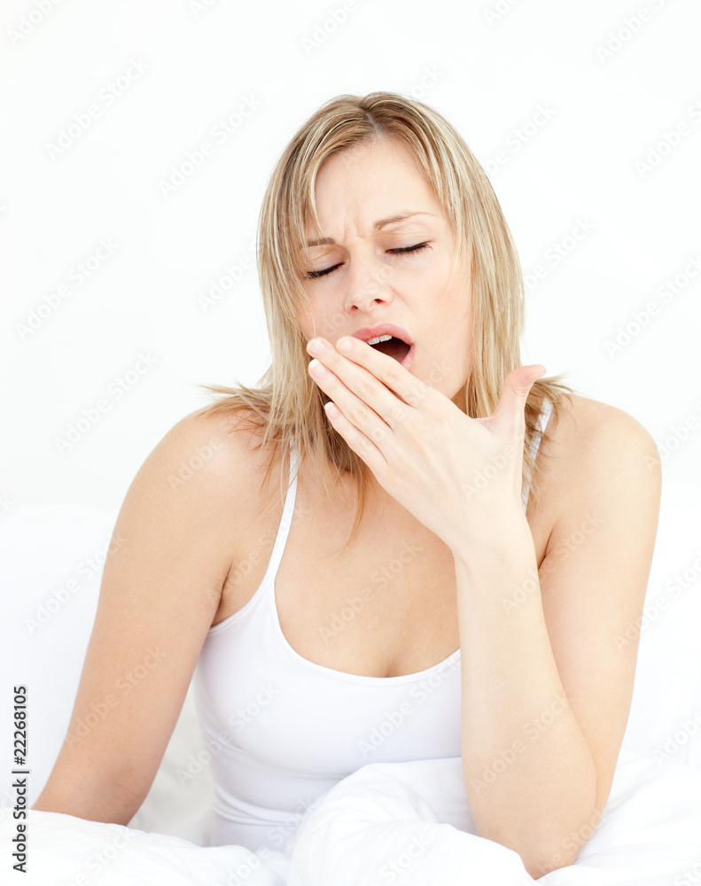 Exhausted woman yawning sitting on her bed Exhausted woman yawning sitting on her bed