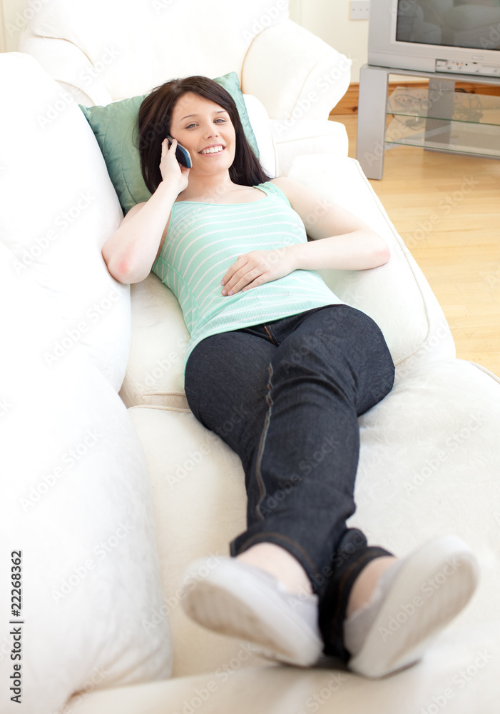 Smiling woman talking on phone lying on a sofa Smiling woman talking on phone lying on a sofa